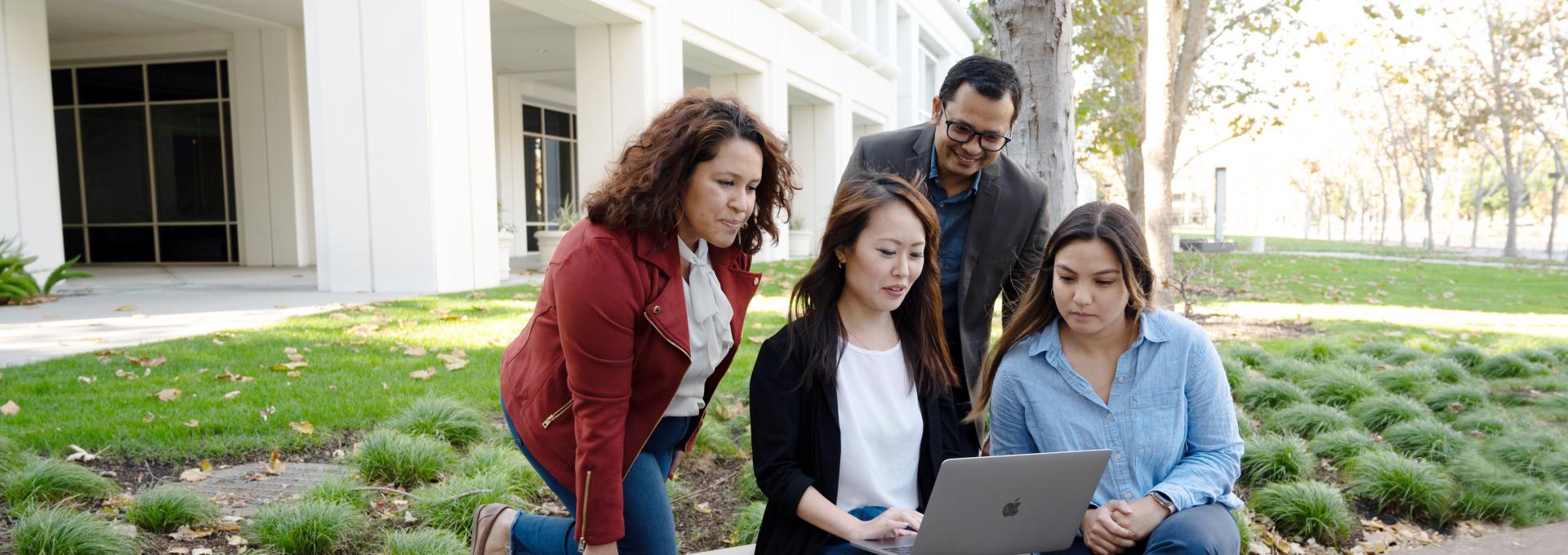 Group of diverse people gathered around a laptop at Bishop Ranch