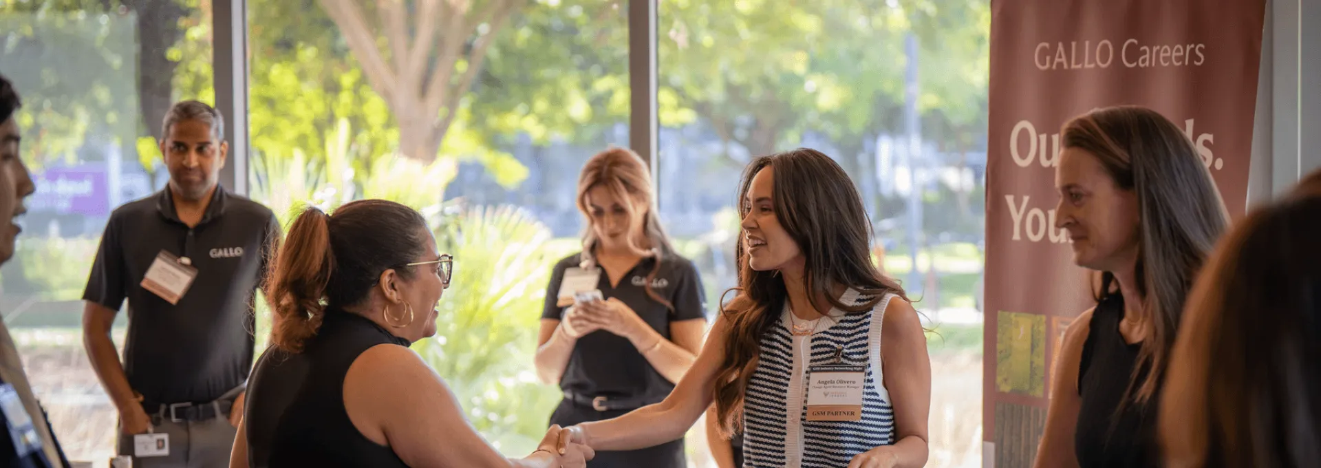 Two women shaking hands at a Gallo Careers job fair booth.