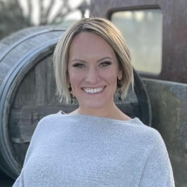 Natalie Frazier in front of wine barrels