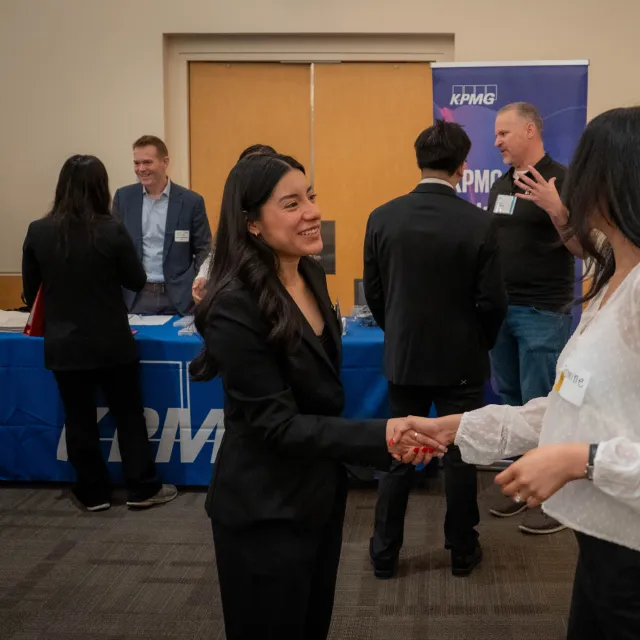 An MPAc student and a recruiter shake hands at the Meet the Firms event