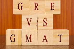 wooden letter blocks stacked on top of each other, spelling out GRE and GMAT