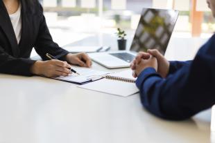 two people sitting at a desk in an office setting