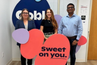 Three people stand in front of an Oobli display sign inside an office, holding colorful cutouts with the phrase “Sweet on you.”