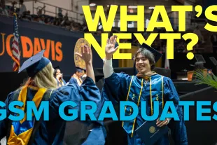 Two UC Davis graduates in caps and gowns high-five at a commencement ceremony. Large text reads "WHAT'S NEXT? GSM GRADUATES.