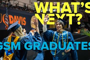Two UC Davis graduates in caps and gowns high-five at a commencement ceremony. Large text reads "WHAT'S NEXT? GSM GRADUATES.