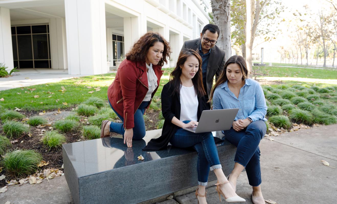 Group of diverse people gathered around a laptop at Bishop Ranch