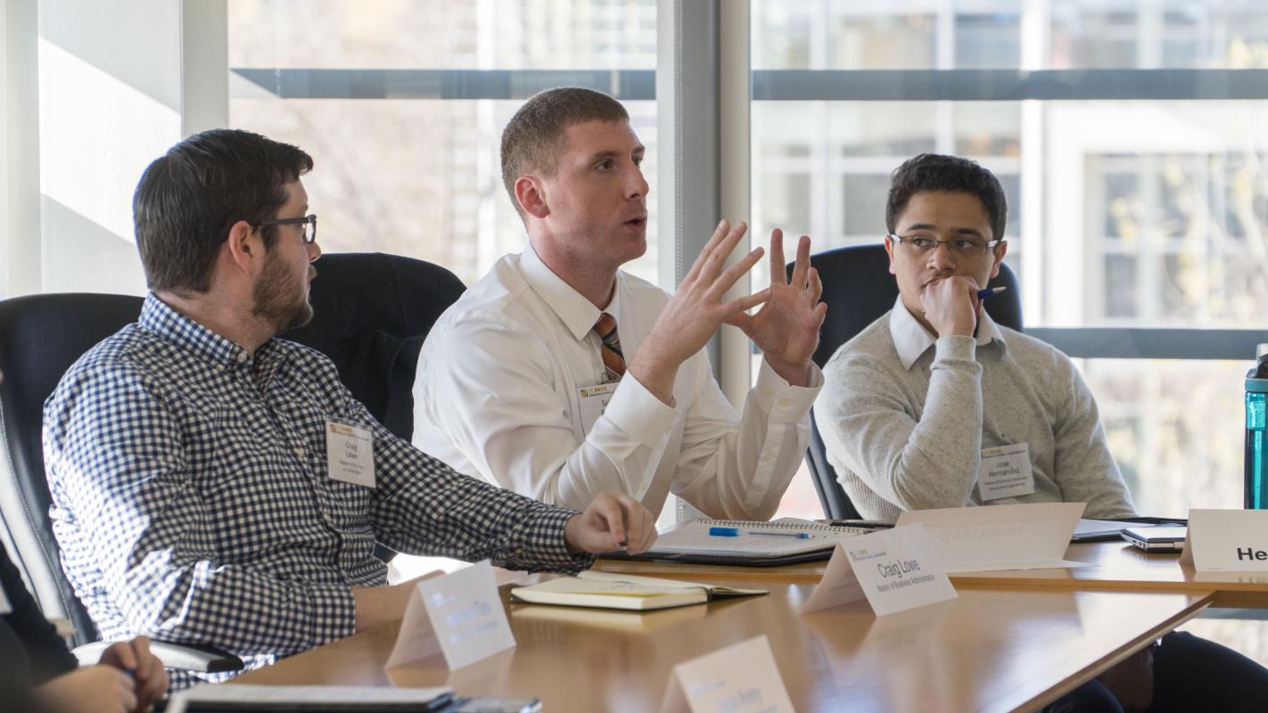 Three people sat at a table in a classroom