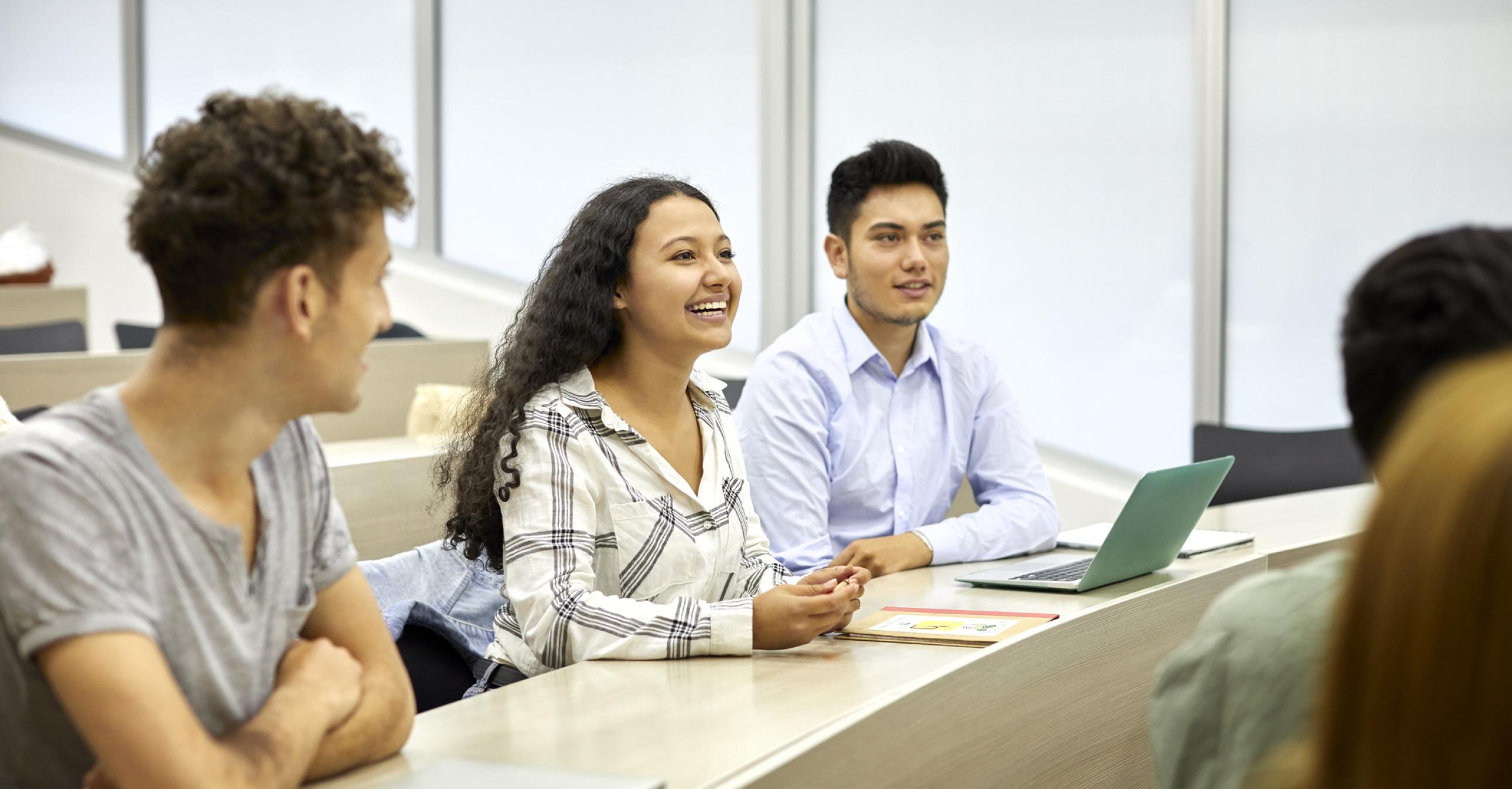 Three students sitting in a classroom smiling