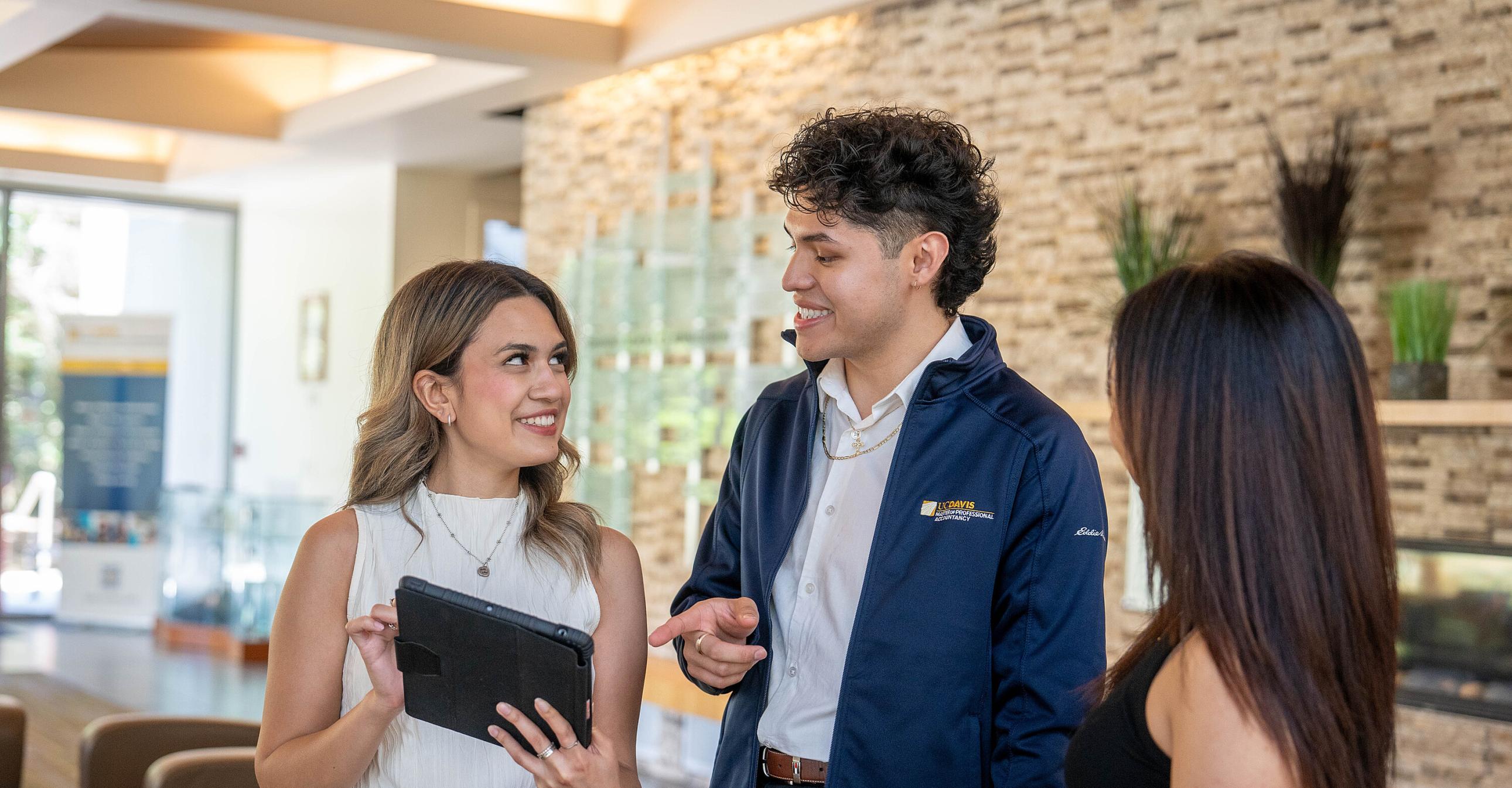 Three MPAc students talking in the Gallagher Hall lobby
