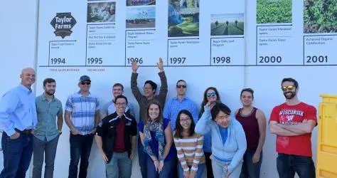Students touring Taylor Fame facilities and standing by a timeline that lists the farm's history