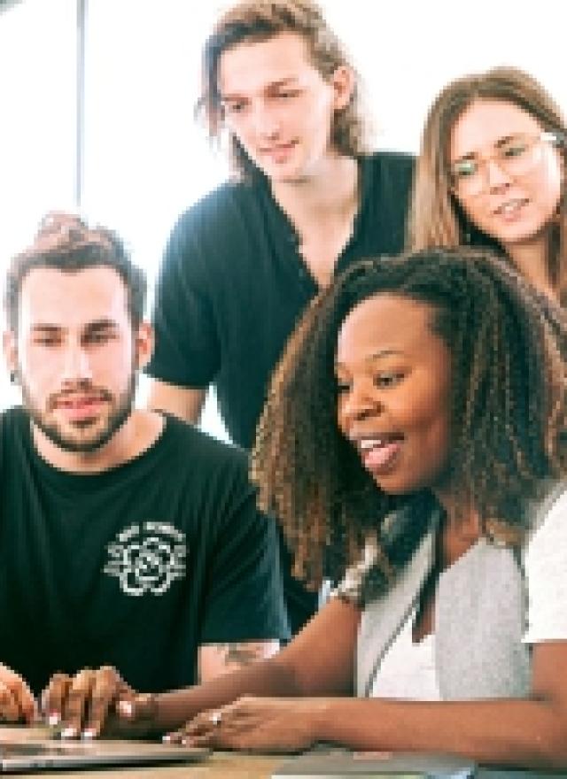 four people in front of a laptop