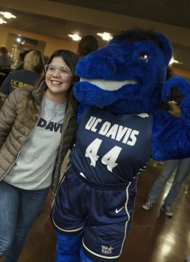 Person standing next to a flexing Gunrock mascot