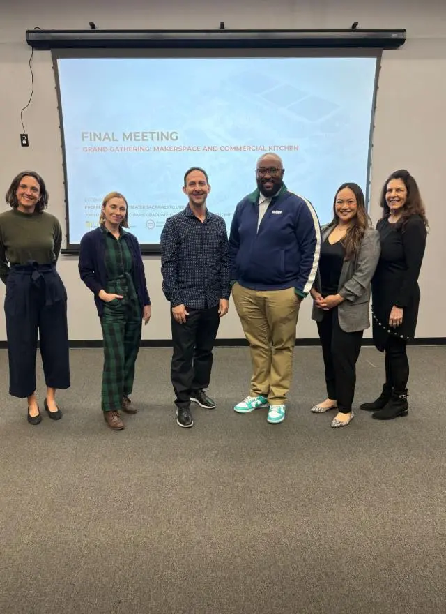 Liza Santa Ana and MBA students in front of a presentation screen