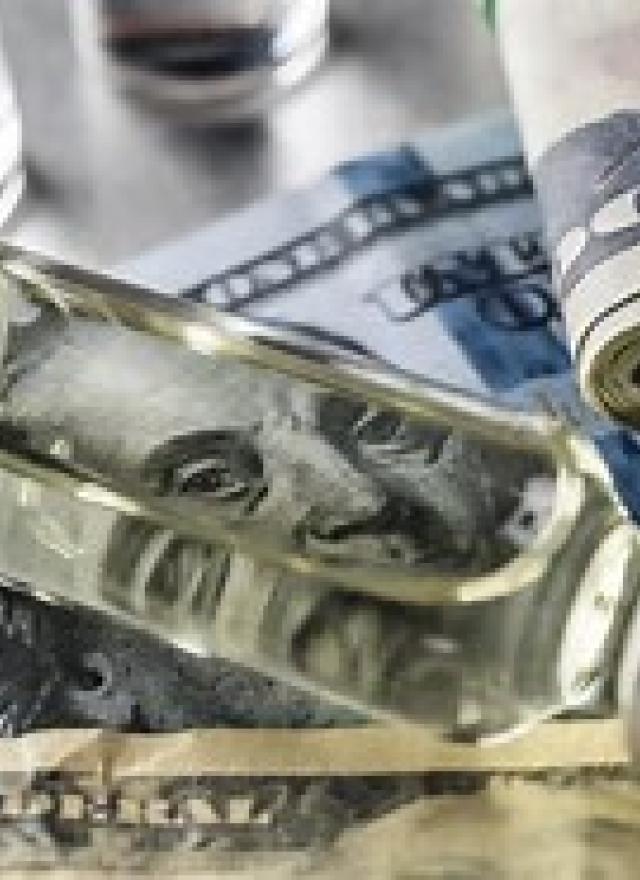 a medical vial on top of a hundred dollar bill