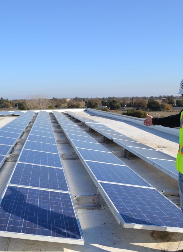 Solar array atop Gallagher Hall at UC Davis with technician pointing