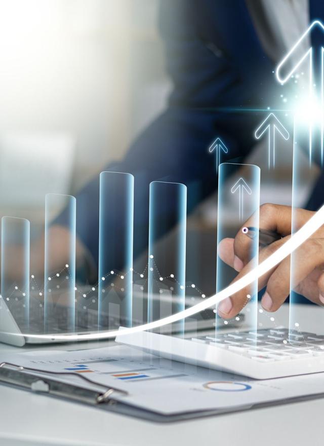 Business professional analyzing financial data on a laptop with a calculator, accompanied by a digital overlay of upward-trending bar graphs and arrows representing growth and success.
