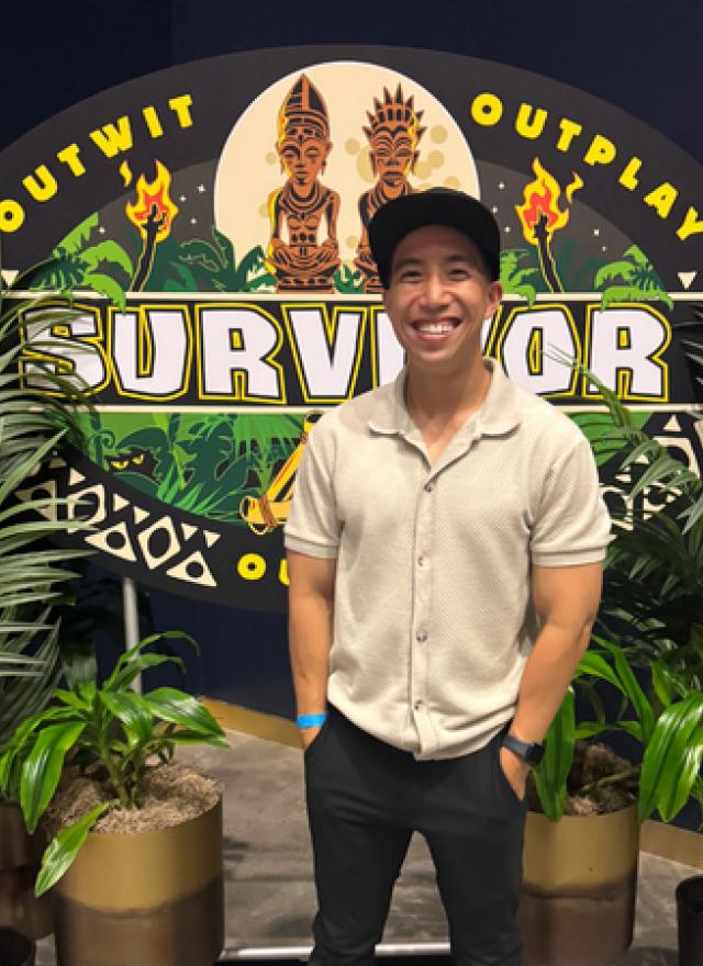 Kevin Leung in front of a banner that reads Survivor