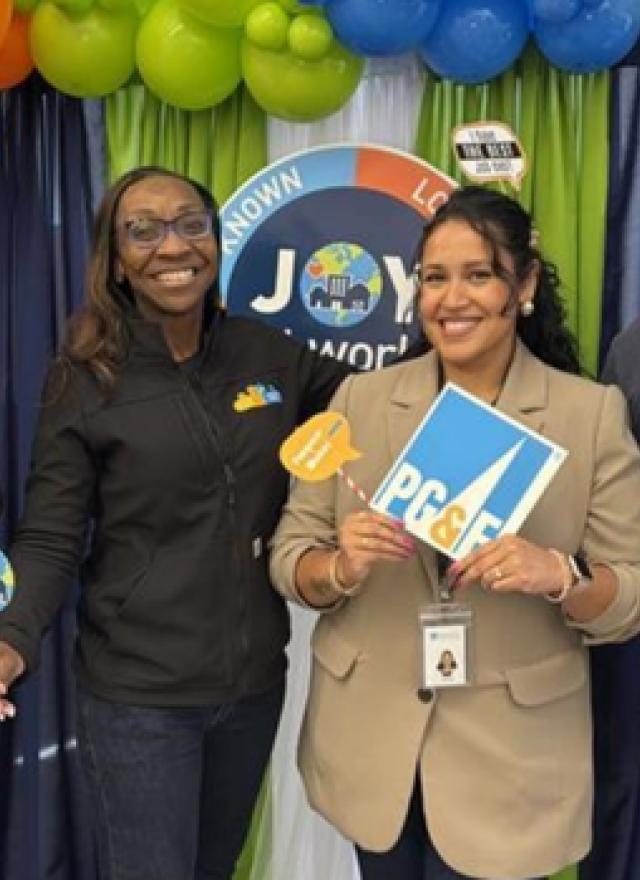 Verenice Andrade with three people, holding up PG&E signage in front a balloon display