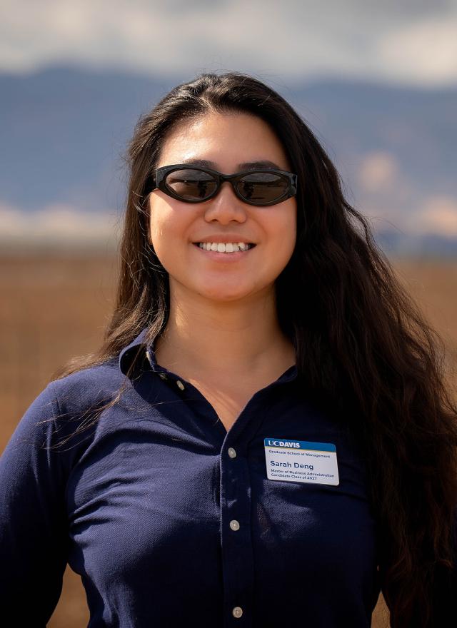 Sarah Deng standing in a field, wearing sunglasses