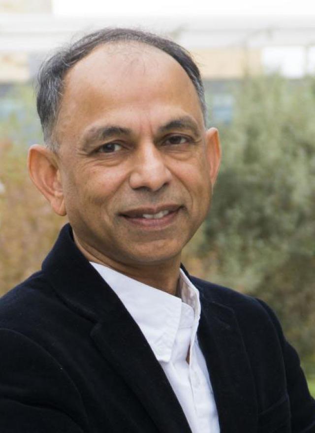 Hemant Bhargava wearing a dark blazer and white shirt, standing outdoors with greenery in the background.
