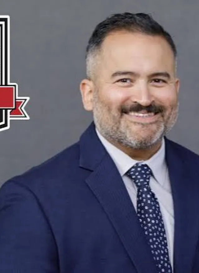 Man in a blue suit smiling beside a “Poets & Quants Online MBA Best & Brightest 2026” badge on a gray background.