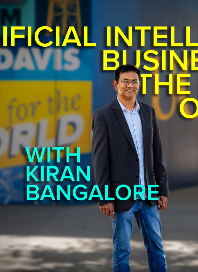 A man in a suit stands outside near a UC Davis mural with the event text “Artificial Intelligence, Business and the Future of Work with Kiran Bangalore” overlaid in large letters.