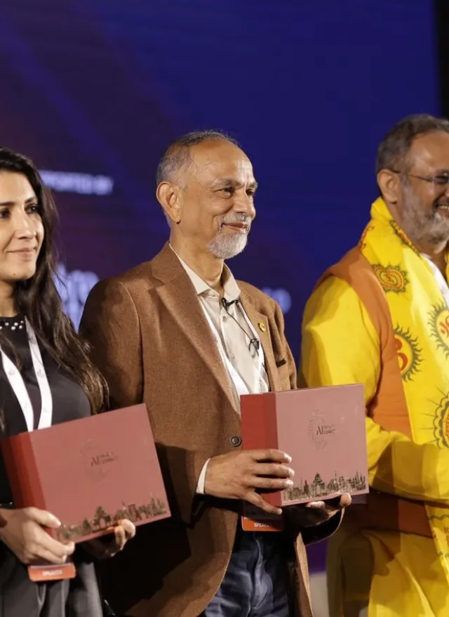 Five people stand on a stage holding matching red commemorative boxes during an awards presentation.