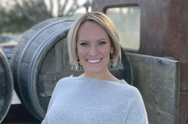 Natalie Frazier in front of wine barrels
