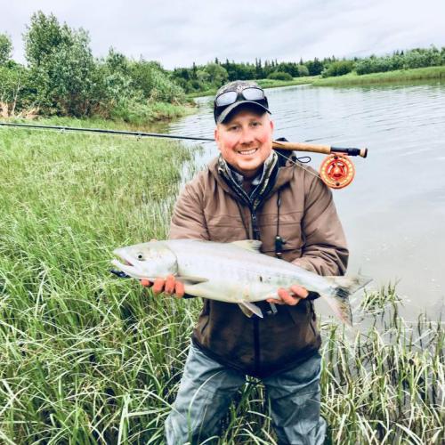 Man holding a fish next to a body of water