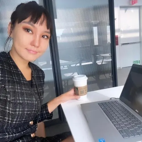 Sodontuya Nerguidavaa sitting in front of a laptop with a coffee in hand