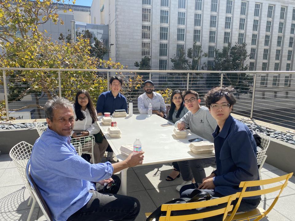 people sitting around a table outside enjoying drinks and food