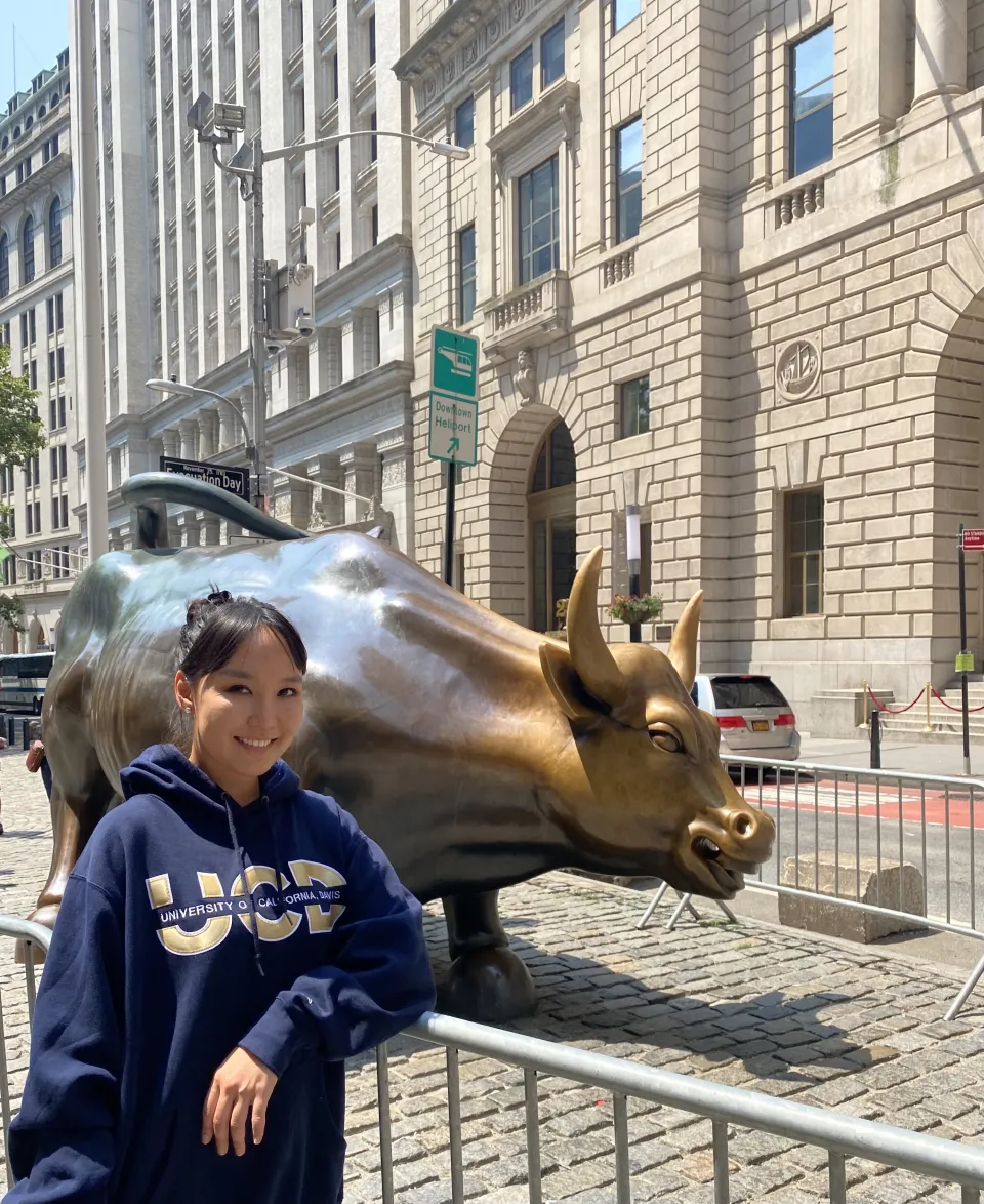 Sodontuya Nerguidavaa leaning on a metal barrier, next to the bull statue on Wall Street