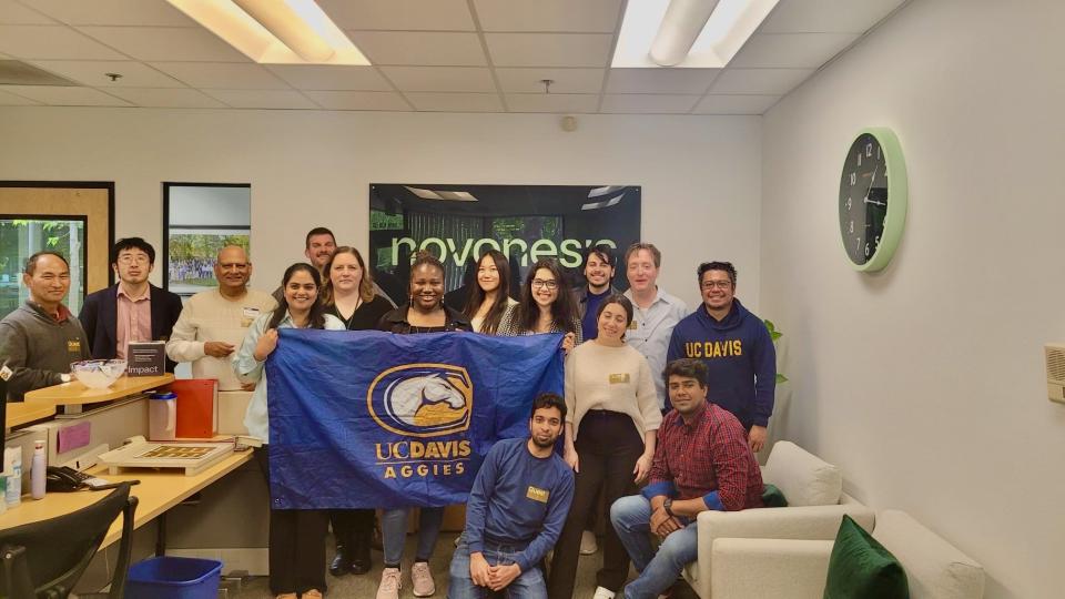 Temidire Dada and MBA students holding a UC Davis banner in Novonesis offices