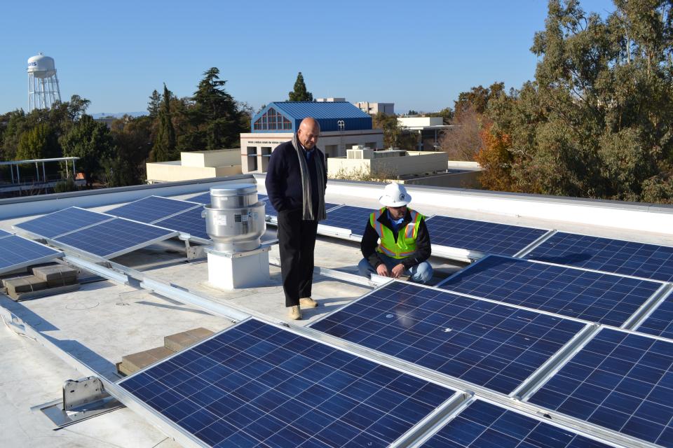 Solar technician and supervisor atop Gallagher Hall roof with solar array