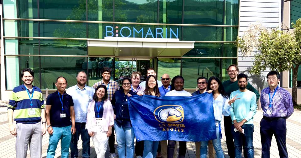 Temidire Dada and MBA students holding a UC Davis banner in front of BioMarin offices
