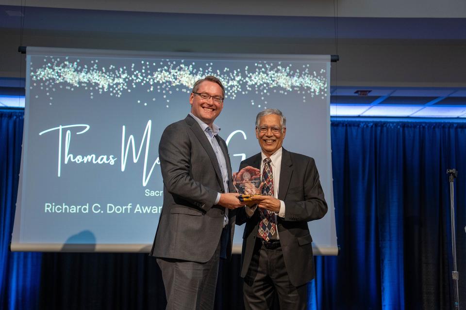 Thomas Modisett Garberson on stage receiving award from Dean Rao Unnava