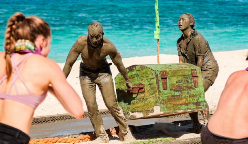 Kevin Leung covered in mud, holding a treasure chest