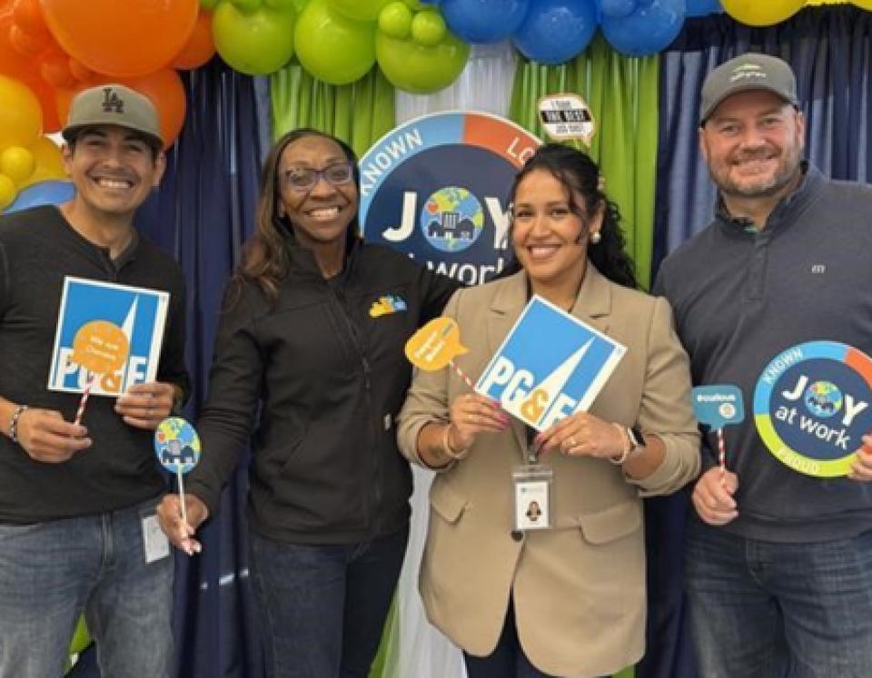 Verenice Andrade with three people, holding up PG&E signage in front a balloon display
