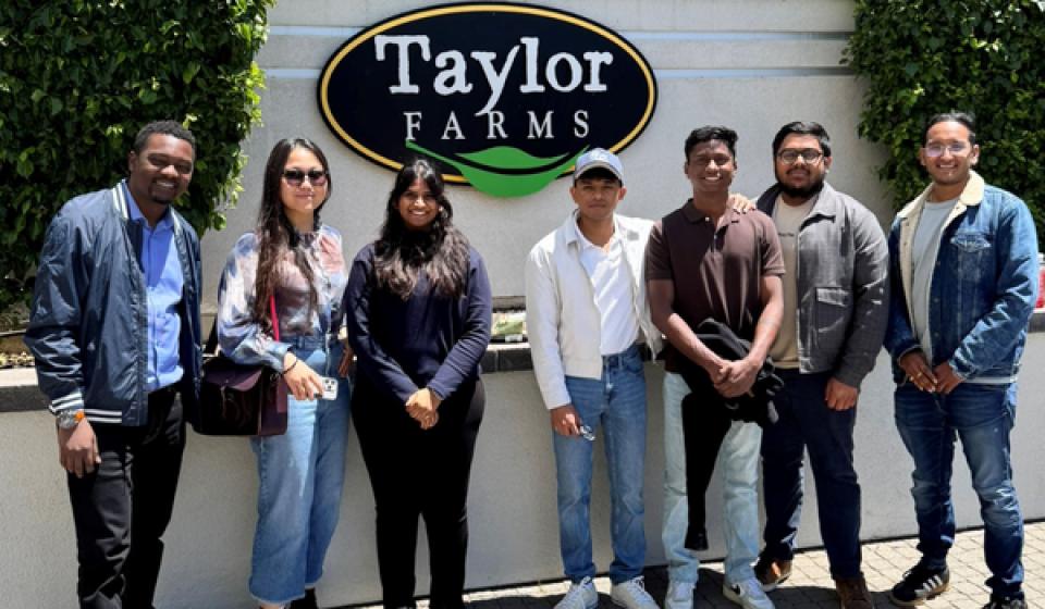 Roshan Paul and MBA students standing in front of Taylor Farms