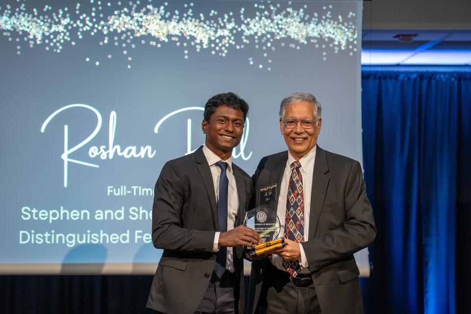 Roshan Paul holding an award on stage with Rao Unnava
