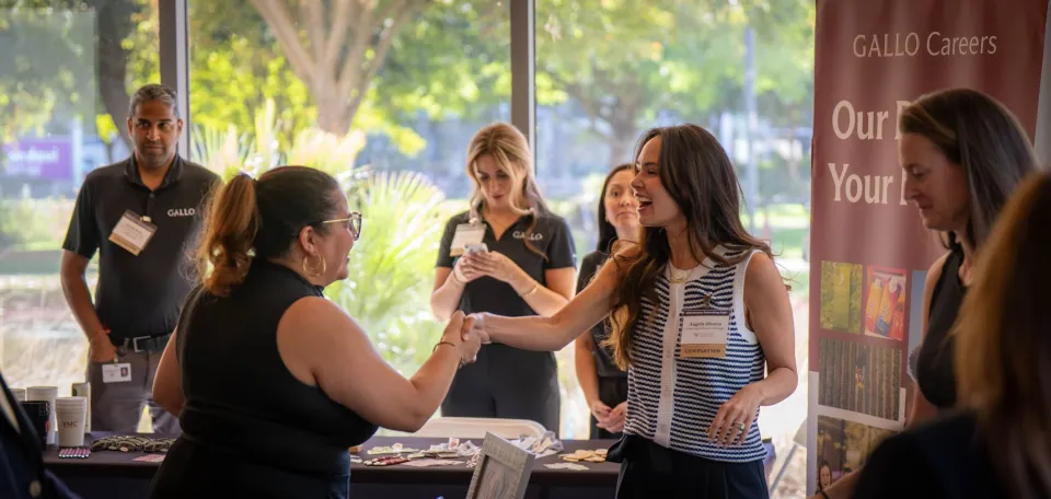 A group of people networking at a professional event, some wearing name tags and holding papers.