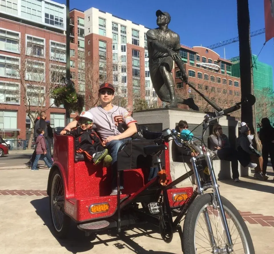 Wesley Chua and his son in the back of a bicycle rickshaw in San Francisco