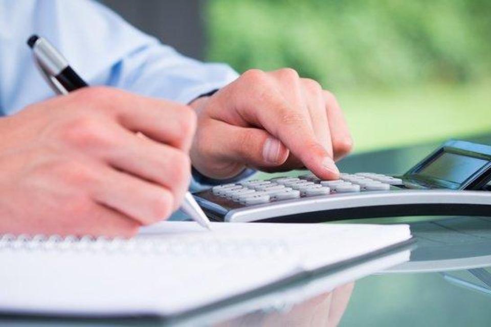 Person using a calculator and writing in a notebook