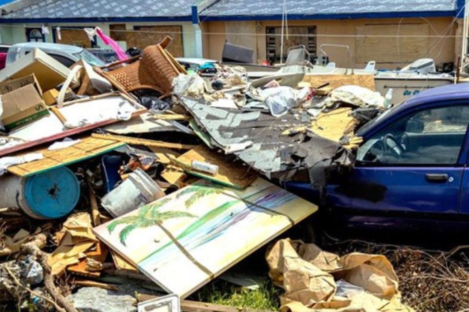 Large amount of garbage in front of a car and house