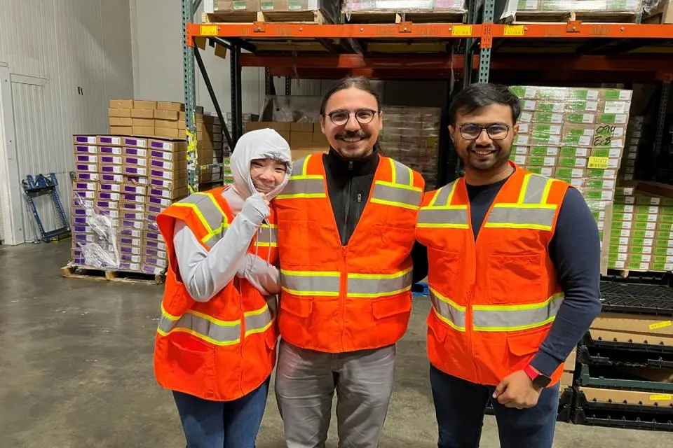 Sayar Banner Banerjee and two other students wearing safety vest at a warehouse