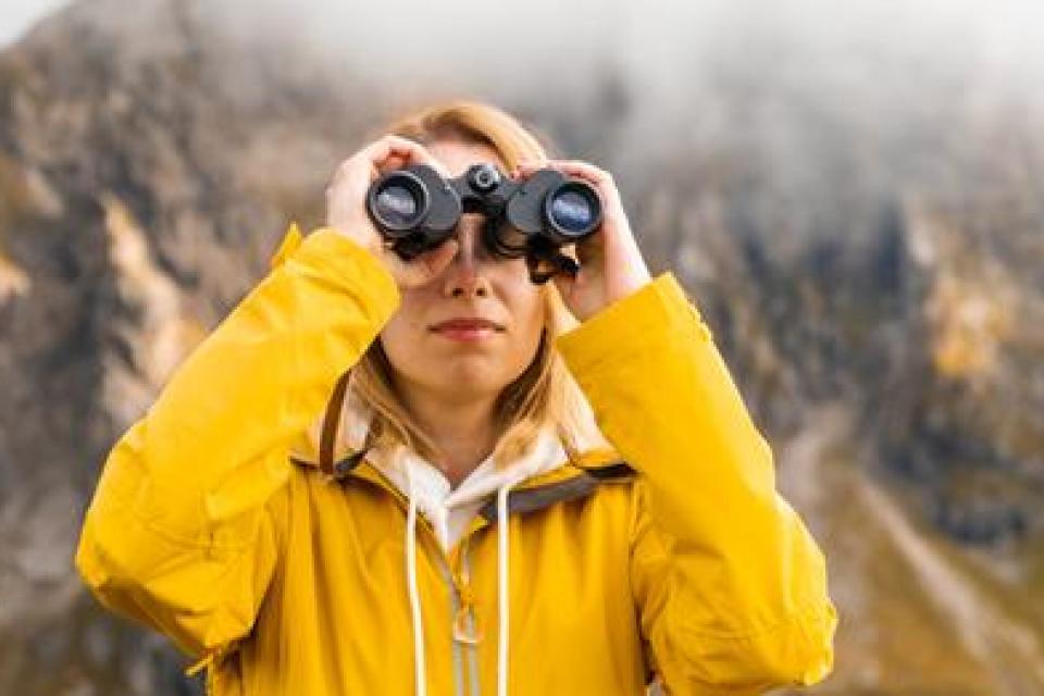 woman looking up through binoculars