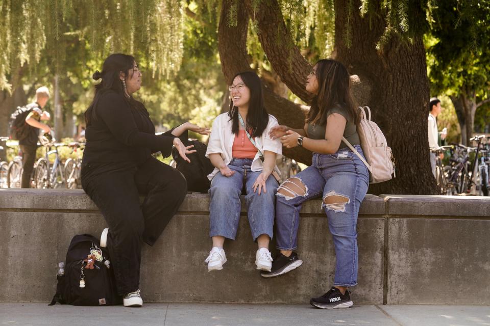 Three students talking and laughing outdoors