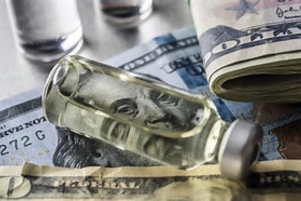 a medical vial on top of a hundred dollar bill