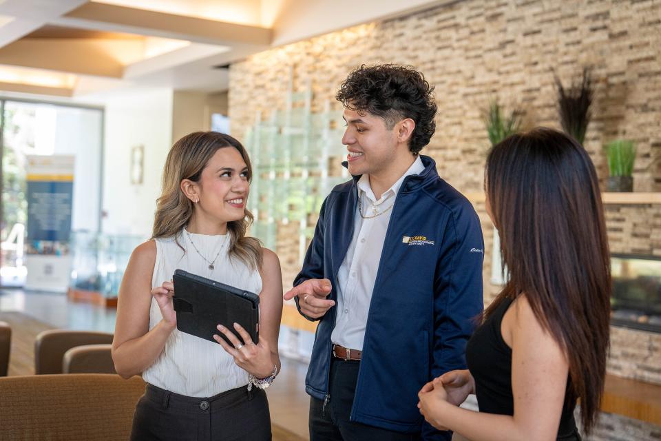Three MPAc students talking in the Gallagher Hall lobby