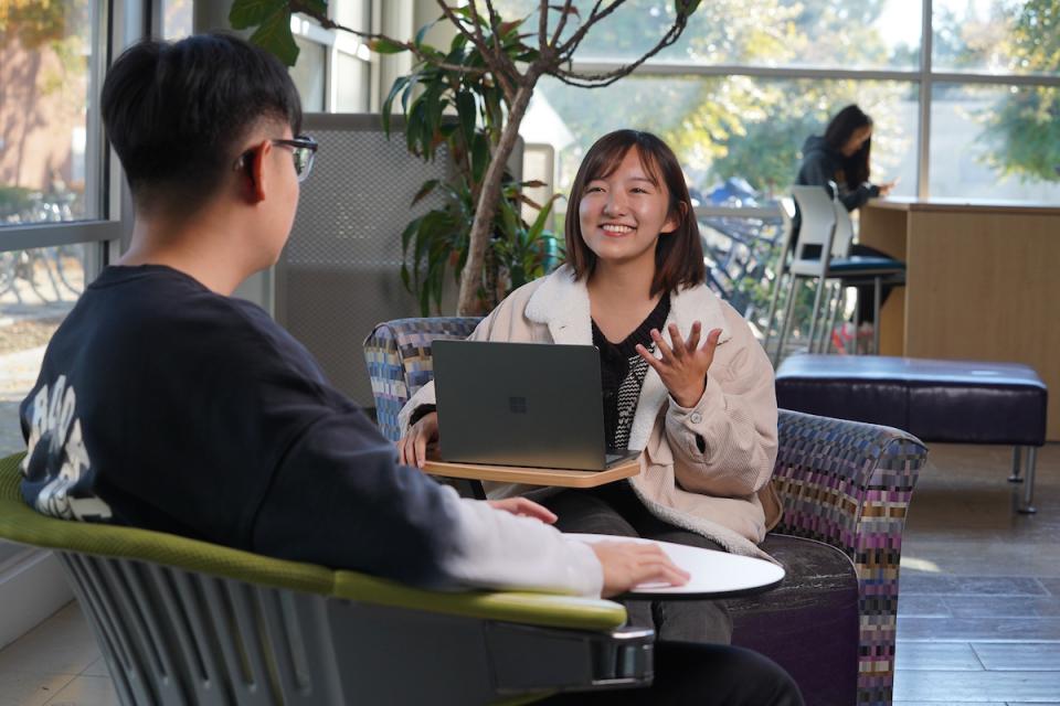 Two students talking, seated in chairs